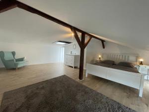 a white bedroom with a bed and a blue chair at Ferienwohnung Hansezauber Lübeck in Lübeck