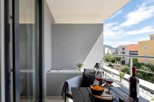 斯普利特Apartman Elena Ekolu的阳台配有带瓶装葡萄酒的桌子。