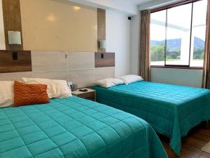 two beds in a room with green sheets and windows at Mviajes Travel & Services in Cajamarca
