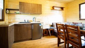 a kitchen with wooden cabinets and a table with chairs at Sielankowe Domki in Rusinowo +7 photos