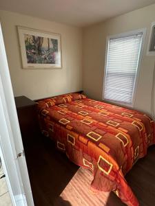 a bedroom with a bed with a red comforter and a window at Shore Beach Houses - 43A Lincoln Ave in Seaside Heights