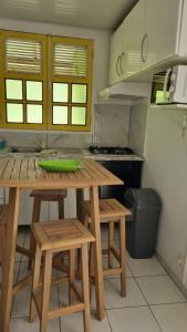 - une cuisine avec des tables en bois et des tabourets dans l'établissement Villa Arc-en-ciel, à Sainte-Luce