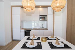 a dining room with a table with chairs and chandeliers at Platán Beach Apartman in Balatonboglár