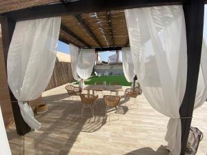 d'une terrasse avec une table, des chaises et des rideaux blancs. dans l'établissement Villa Fumarel, à Matalascañas