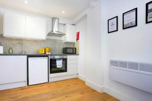 una cucina con armadi bianchi e lavandino di Central Buckingham Apartment #5 with Free Parking, Pool Table, Fast Wifi and Smart TV with Netflix by Yoko Property a Buckingham