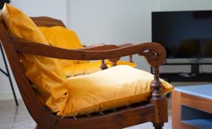 a wooden chair with yellow cushions on it at Mas Grenadine, magnifique villa du Piémont Cévenol in Sauve