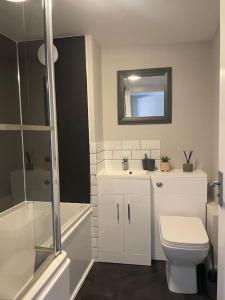 La salle de bains est pourvue de toilettes, d'un lavabo et d'un miroir. dans l'établissement Oak House - 3bed Townhouse with free parking by ShortStays4U, à King's Lynn