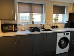 a kitchen with a counter top with a washing machine at Oak House - 3bed Townhouse with free parking by ShortStays4U in Kings Lynn