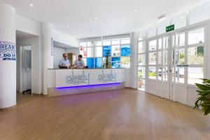 two men standing at a counter in a building at Jutlandia Family Resort in Santa Ponsa