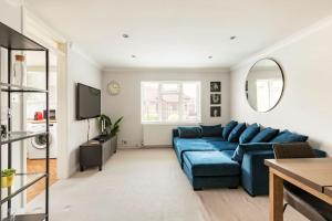 a living room with a blue couch and a tv at Spacious light flat in fantastic location! in Eton