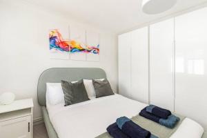 a white bedroom with a bed and a chair at Spacious light flat in fantastic location! in Eton