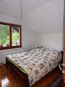 Rožaje的住宿－Weekend house Grahovača，一间卧室配有一张带花卉棉被的床和窗户。