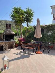 a patio with a table and an umbrella and a fire place at Backyard houses in Toroni