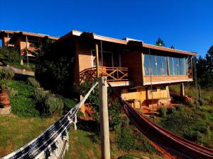 a house on a hill with a hammock in front of it at Chalé Ganesh - O chalé é maravilhoso! in Cunha
