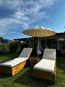 two beds and an umbrella in the grass at La casa di mare in Agios Gordios