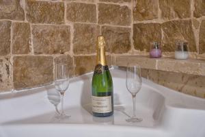 una bottiglia di champagne e 2 bicchieri di vino in una vasca da bagno di Dimora Dante a Ceglie Messapica