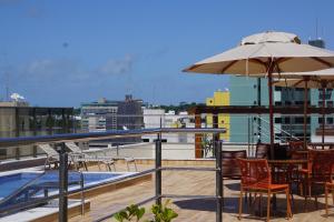 a balcony with tables and chairs and an umbrella at Flat Buenos Ayres Cabo Branco in João Pessoa