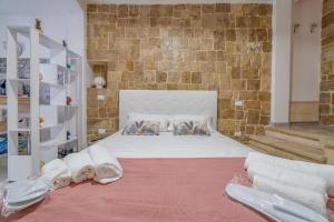 una camera con un letto bianco e un muro di mattoni di Dimora Dante a Ceglie Messapica