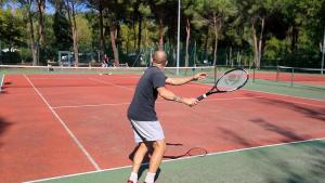 un hombre sosteniendo una raqueta de tenis en una pista de tenis en Appartement dans village vacances, en Ghisonaccia