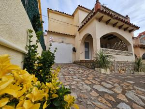 een huis met gele bloemen voor een oprit bij Casa Sebastian in L'Escala