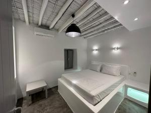 a white bedroom with a bed and a lamp at Naoussa Center Home in Naousa