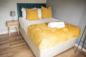 a bed with yellow pillows and a yellow blanket at Luxury Cityscape London - Free Parking! in Ealing