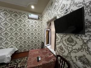 a room with a tv on the wall and a table at Dilnura Guest House in Bukhara