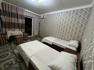 una camera d'albergo con due letti e un tavolo di Dilnura Guest House a Bukhara