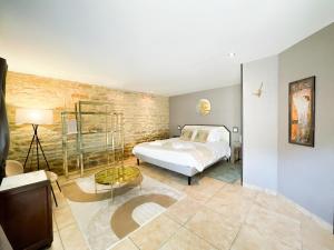 a bedroom with a white bed and a brick wall at La Ferme du Bois - Piscine et Spa in Plottes