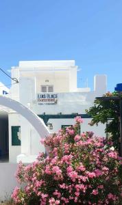 a white building with a sign on it with pink flowers at Ilias Place in Ios Chora