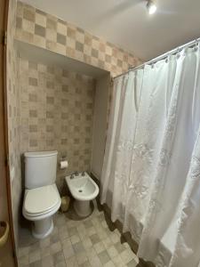 a bathroom with a toilet and a shower curtain at Santa Fe Suites Apart in Salta +30 photos
