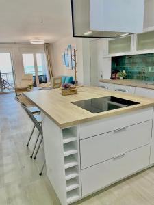 uma cozinha com um balcão com um lavatório e cadeiras em Blue house 1ª linea playa em Torrevieja