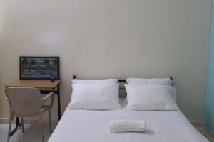 - une chambre avec un lit doté d'oreillers blancs et d'une table dans l'établissement Résidences PRIMIS Thiès - appartements et chambres, à Thiès