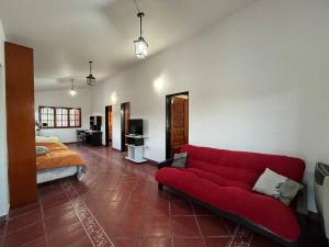 a living room with a red couch and a bed at Don Norber, hermosa casa de descanso. Río Ceballos in Río Ceballos