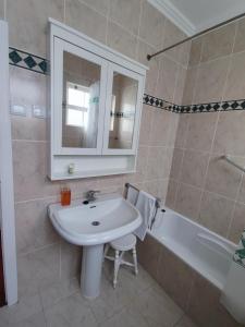 a bathroom with a sink and a mirror and a tub at Casa do Paúl in Santa Cruz da Graciosa