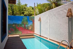 a swimming pool next to a wall with a painting at Milagres de Minas in São Miguel dos Milagres
