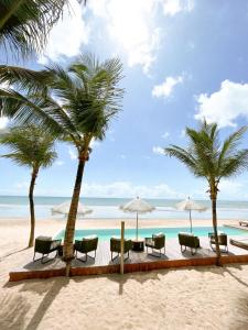 een strand met stoelen en palmbomen en de oceaan bij Villa Mango in Icaraí