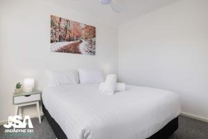 a bedroom with a white bed with a picture on the wall at Berridale Bliss in Berridale