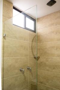 La salle de bains est pourvue d'une douche en verre et d'une fenêtre. dans l'établissement Praia Apartaestudios Sabaneta, à Sabaneta