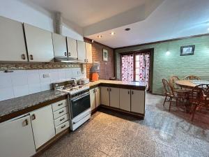 a kitchen with white cabinets and a table with chairs at Casa en SAN LUIS in San Luis