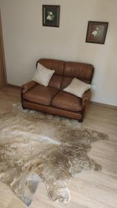 um sofá de couro castanho sentado numa sala de estar com um tapete em Quarto Amélia em Fogueira