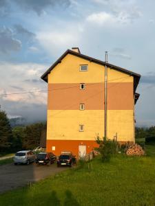 a large building with cars parked in a parking lot at Apartament pod Honem in Cisna