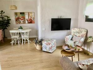 ein Wohnzimmer mit einem TV, Stühlen und einem Tisch in der Unterkunft Santa Clara Bungalows in Maspalomas