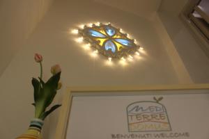 un lampadario a braccio con luci sul soffitto con una pianta di Mediterre Domus a Casamassima