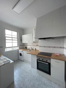 een witte keuken met witte kasten en een raam bij Atico Vintage con Terraza in Vigo