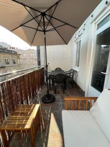 eine Terrasse mit einem Tisch und einem Sonnenschirm auf dem Balkon in der Unterkunft Atico Vintage con Terraza in Vigo
