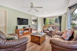 a living room with leather furniture and a flat screen tv at Halls on Falls Homestead in Strath Creek