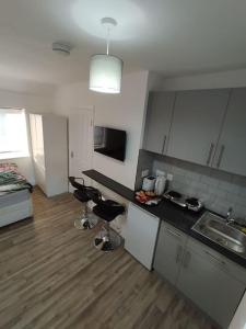 a kitchen with a sink and two stools in a room at Stylish studio flat with Parking in Enfield