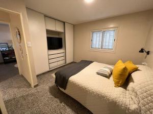een slaapkamer met een bed met gele kussens en een televisie bij CASA EN YERBA BUENA in Yerba Buena