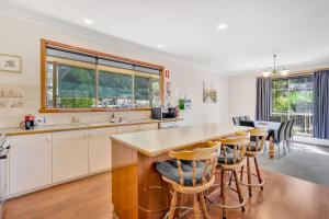 a kitchen with white cabinets and a counter with bar stools at Halls on Falls Homestead in Strath Creek